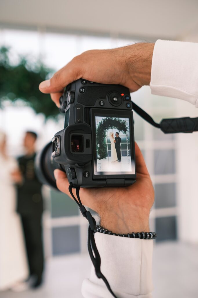 Photographer taking a photo of bride and groom. Photo can be seen on camera screen. Wedding Photographer Meeting Checklist